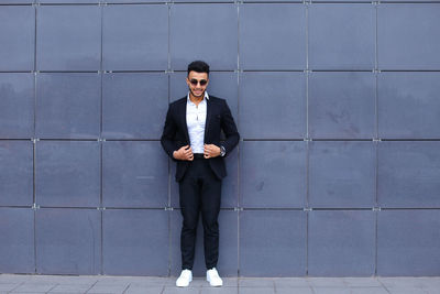 Portrait of businessman standing against wall