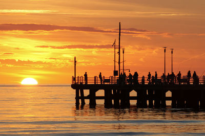 Silhouette pier over sea against sky during sunset