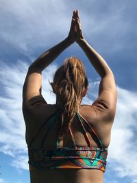 Low angle view of woman with hands clasped against sky