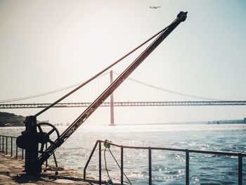 Suspension bridge over sea against clear sky