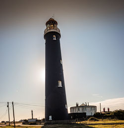 Low angle view of lighthouse by building against clear sky