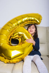 Portrait of smiling woman sitting against yellow wall