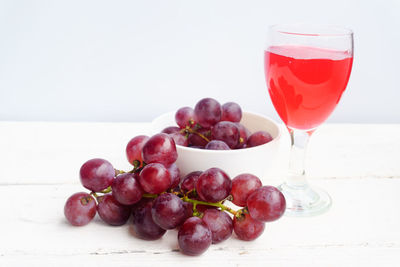 Close-up of red grapes with juice in glass on table