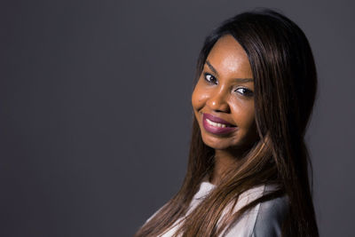 Portrait of young woman against black background