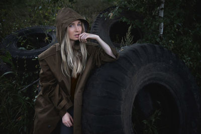 A woman in a brown raincoat is sitting near the big wheel