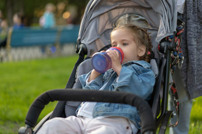 Girl drinking milk while sitting in baby stroller