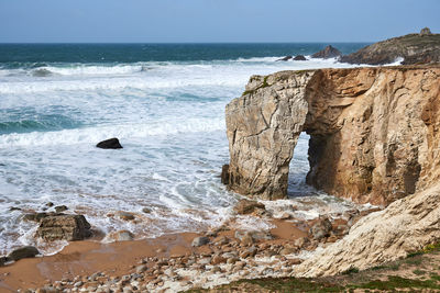 Waves of the atlantic ocean break at the port blanc rock bridge with spouting gout on quiberon