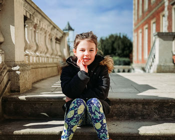 Portrait of young woman standing against building