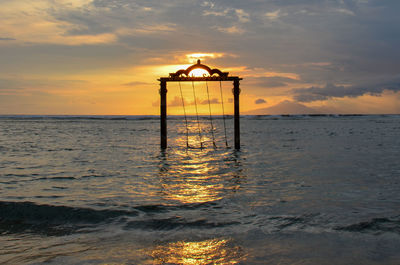 Lifeguard hut on beach against sky during sunset