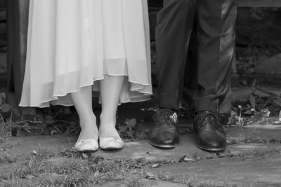 Low section of wedding couple standing outdoors