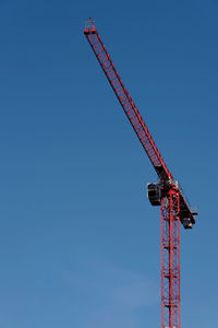 Low angle view of crane against clear blue sky