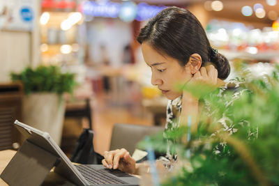 Concentrated beautiful woman using laptop computer in cafe.