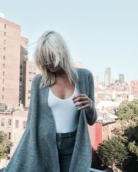 Rear view of woman standing by cityscape against clear sky