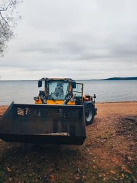 Scenic view of beach against sky with working machine 