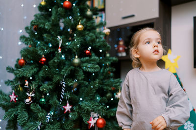 Young woman decorating christmas tree at home