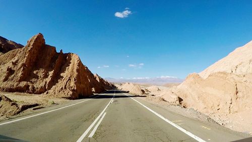 Road leading towards mountains against sky