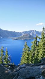 Scenic view of lake and mountains against clear blue sky