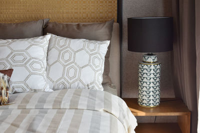 Pillows on bed by electric lamp at home
