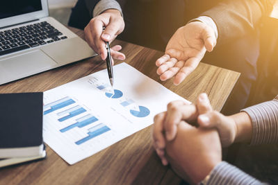 Colleagues discussing over graph at desk in office