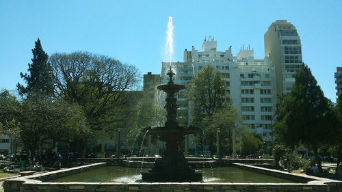 Fountain in city against clear sky