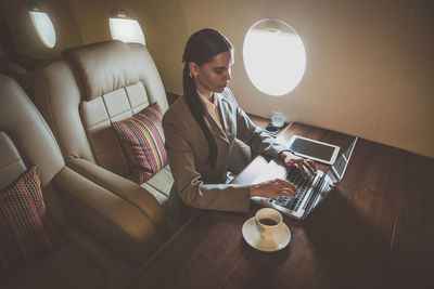 High angle view businesswoman using laptop in airplane