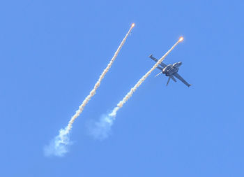 Low angle view of airshow against clear blue sky