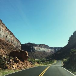 Road by mountain against clear blue sky