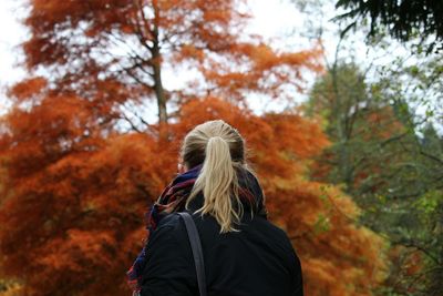 Rear view of woman standing against autumn trees