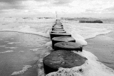 Wooden posts on beach against sky