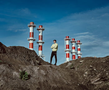 Low angle view of young man standing on rock against sky