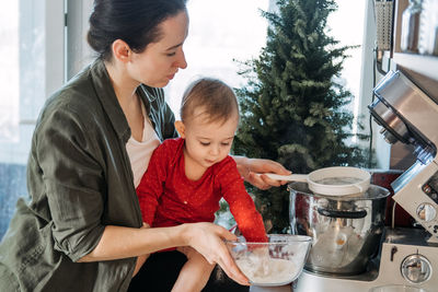 Cozy christmas at home. family preparation holiday dessert. mother and baby toddler daughter play