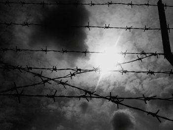 Low angle view of silhouette barbed wire against sky