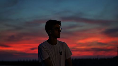 Silhouette man standing against orange sky