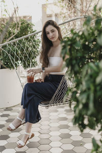 Portrait of woman sitting on chair against plants