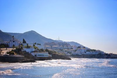 Scenic view of sea and mountains against clear blue sky