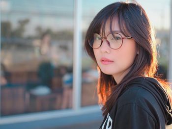 Portrait of woman in eyeglasses against glass window