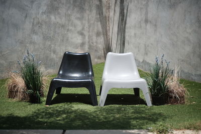 Empty chairs on field against wall