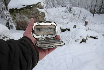 Midsection of person holding snow on field