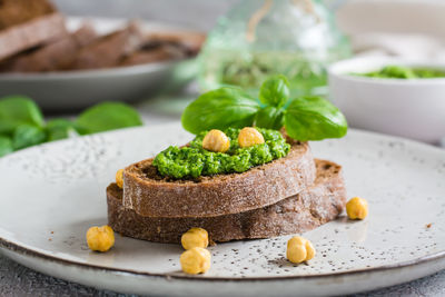 Fresh sandwich with pesto and chickpeas on rye bread on a plate on the table. italian homemade 