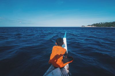 Rear view of man standing in sea against sky