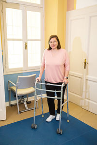 Full length portrait of woman with mobility walker at home