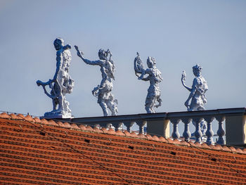 Low angle view of sculpture on roof against building