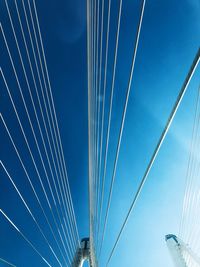 Low angle view of suspension bridge cables against blue sky