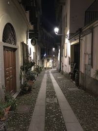 Empty alley amidst buildings in city at night