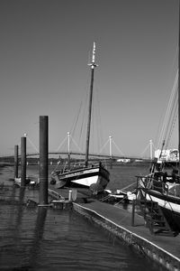 Boats moored at harbor against clear sky