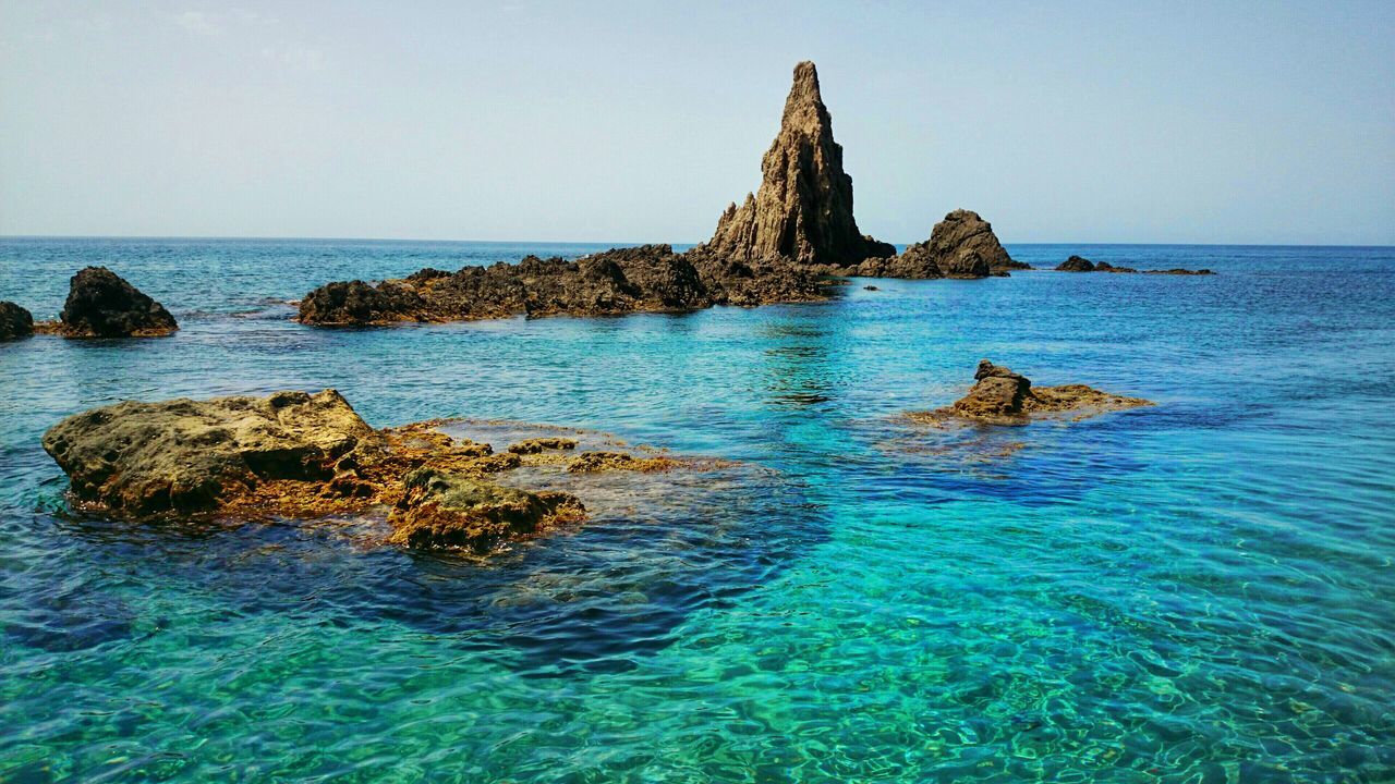 sea, water, horizon over water, clear sky, tranquility, tranquil scene, scenics, rock - object, beauty in nature, rock formation, nature, blue, cliff, idyllic, copy space, beach, rock, sky, day, rippled