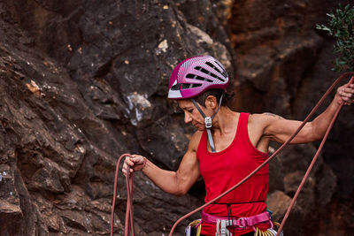 Active senior woman wearing prism glasses while holding climbing rope