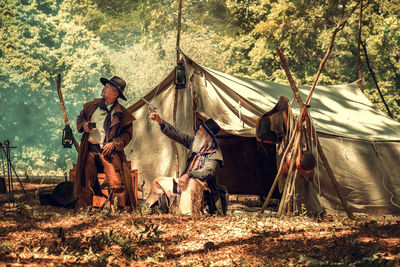 People sitting on field in forest