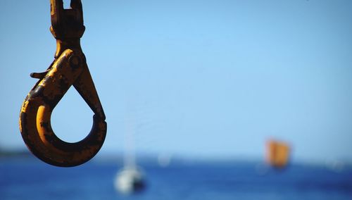 Close-up of iron hook against clear blue sky