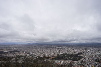 Aerial view of cityscape against cloudy sky